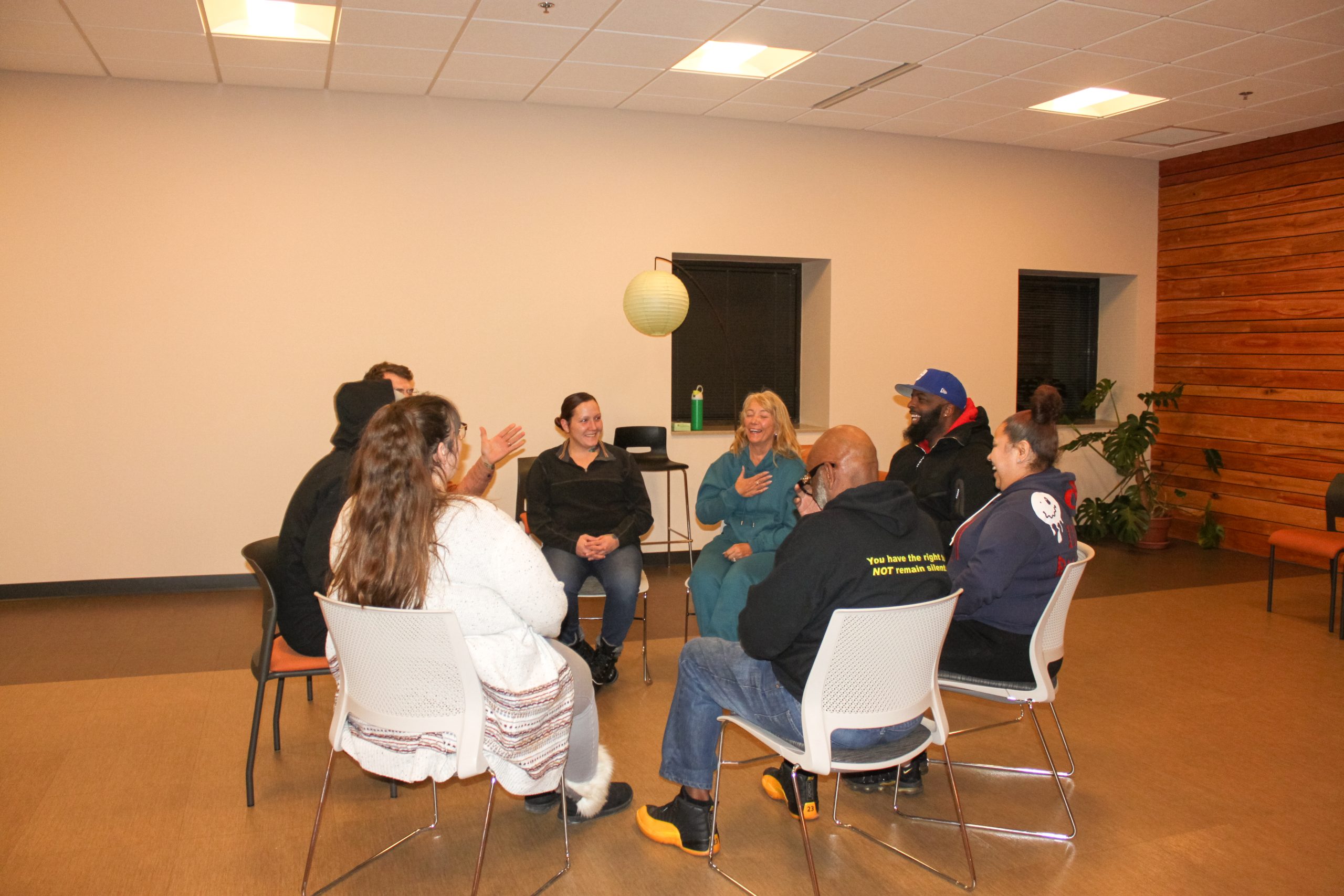 A group sits in a circle in the meditation room sharing laughter.
